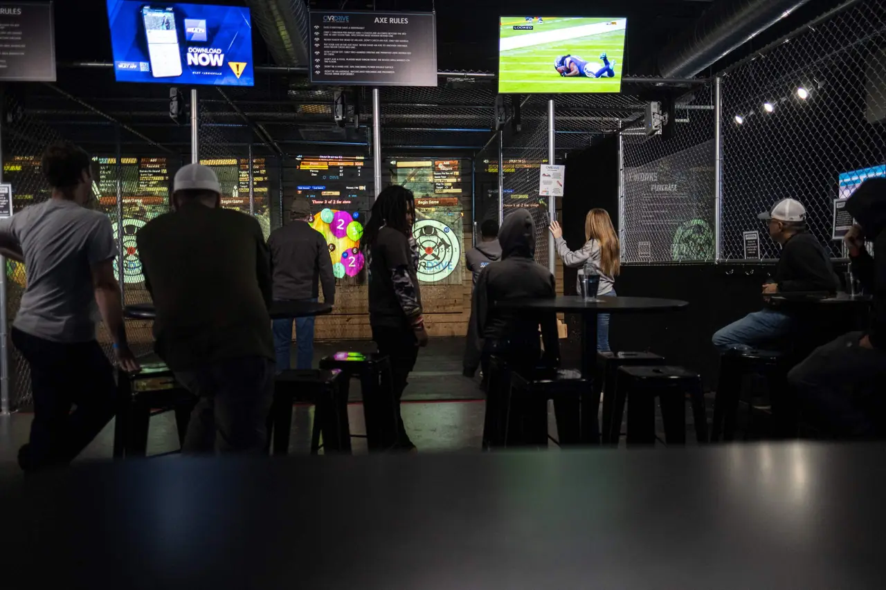 Guests throwing axes with drinks at the rail