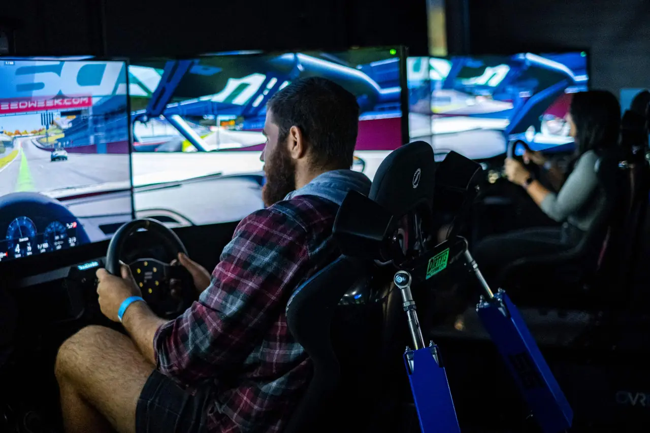 A guest laughing behind the wheel of a racing simulator